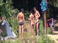 Nu1253#Company of two guys and a girl sunbathe and drink beer by the river. They have a fun.