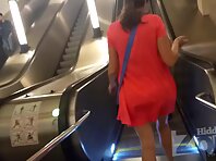 Up4420#A tanned girl in a short red dress is seen under her skirt. Our cameraman brazenly sl
