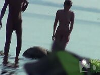 Nu1487#A couple walks along the surf line. They are laughing and holding hands. Nude beach v